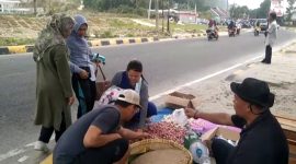 Ruspan (47), pedagang sembako sedang melakukan transaksi di depan Kantor Pemkab Pesisir Barat.
Foto: KabarIndonesia.co