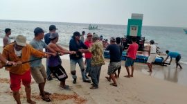 Warga Pulau Tabuan, Kabupaten Tanggamus bergotong royong menepikan unit genset pembangkit listrik yang baru. Foto: Nafian Faiz, Kabar Indonesia