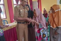 Pj. Peratin Gedung Surian, Calim menyerahkan bantuan langsung tunai (BLT) Dana Desa Tahun 2023 pada 23 KPM. Foto: Kristian Agusani, Kabar Indonesia.