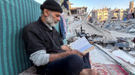 Seorang pengungsi Gaza membaca Al-Qur'an di tengah reruntuhan Rafah. Foto: Reuters