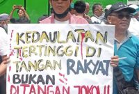 Seorang massa aksi di depan Gedung DPR RI Senayan membentangkan poster tuntutan dalam aksi massa yang berlangsung pada Jum'at (1/2/2024). Foto: Rizky Pratama Saputra, Kabarindonesia.co