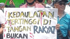 Seorang massa aksi di depan Gedung DPR RI Senayan membentangkan poster tuntutan dalam aksi massa yang berlangsung pada Jum'at (1/2/2024). Foto: Rizky Pratama Saputra, Kabarindonesia.co